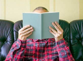 A man reading, with the face covered by the book