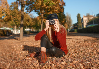 Beautiful young woman with modern photo camera in autumn park