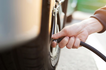 close up hand man car parking a check and inflate the tire fill up the air for safe driving on the...