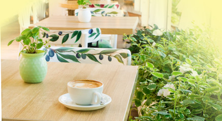 white cup with coffee on the table, in the morning, in a cafe on a bright veranda, close-up, selective focus, soft bluer.
