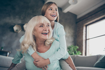 Low angle view photo of two best friends people cute aged granny small grandchild girl hug piggyback playing funny game spend weekend together house indoors