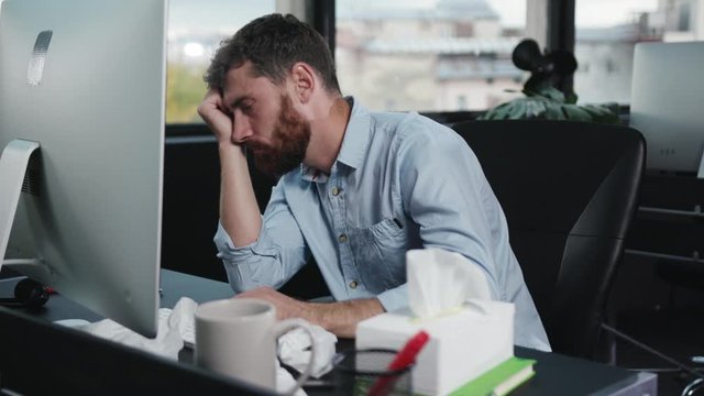 Sleepy overworked young business manager yawning falling asleep on office table. Caucasian workaholic is tired of long hours at work.