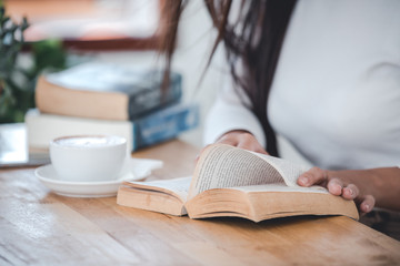 A beautiful woman wearing a white T-shirt reading a wooden table in a white room.