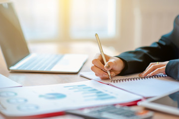 A woman is working on a notebook with a graph paper in an office.