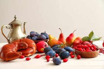 Beautiful autumn composition with harvest, tasty crescents and teapot on white table