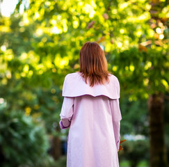 the girl is brown-haired, walks in the Park in the autumn, in a leather, stylish skirt,and a pink autumn cloak, with a leaf in her hand