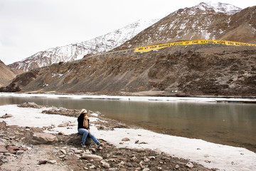 Fototapeta na wymiar Travelers thai woman travel visit and posing portrait for take photo at view point of Confluence of the Indus and Zanskar Rivers while winter season at Leh Ladakh in Jammu and Kashmir, India