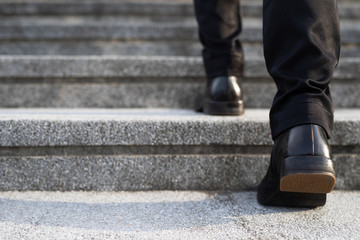 modern businessman working  close-up legs walking up the stairs in modern city. in rush hour to...