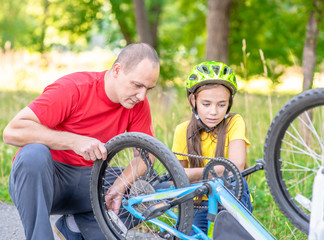 Father helps his daughter pump a bicycle wheel