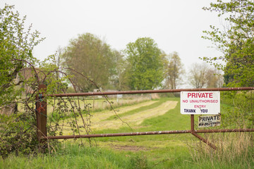 hallow focus of a makeshift Private Property sign seen at the entrance to private pasture. Secured by a metal gate to prevent trespassers during darkness.
