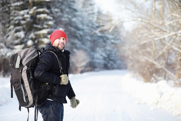 Fototapeta na wymiar A man travels with a backpack. Winter hike in the forest. Tourist on a walk in the winter in the park.