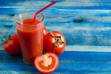 Tomato juice in a clear glass and tomatoes on a wooden background Kopi space