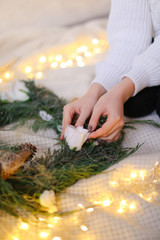 Female hands, green wreath and twinkling yellow garlands.