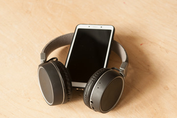 White smartphone with headphones on an old wooden board