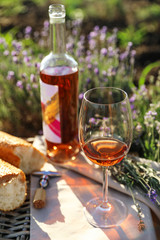 Composition with glass of wine on wicker table in lavender field