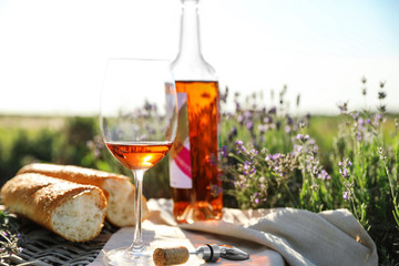 Composition with glass of wine on wicker table in lavender field. Space for text