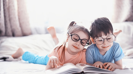 Children lie on the bed next to the newborn baby, little sister.