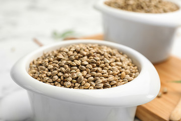 Organic hemp seeds in bowl on table, closeup