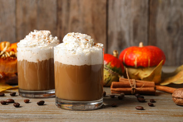 Glasses with tasty pumpkin spice latte on wooden table