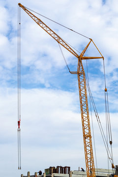 Construction site with a crane and builders on concrete structures against the sky with clouds