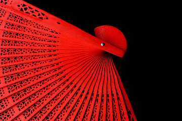 Red fan with a pattern closeup. Isolate on black background