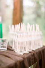 Bottles for lemonade on the wooden table outdoors. Set of glass bottles for lemonade and cocktails. Catering, wedding reception concept.