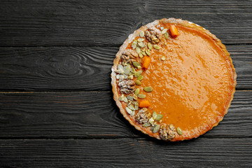 Delicious fresh homemade pumpkin pie on black wooden table, top view. Space for text
