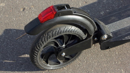 Red rear stop tight and molded wheel of black electric portable kick scooter close up