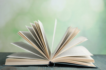 Open book on blue wooden table against blurred green background