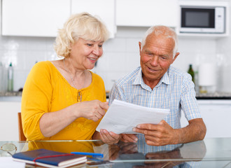 Mature couple in home interior filling up documents at home