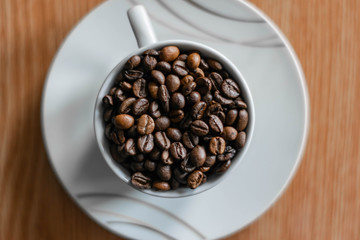 white cup full of coffee beans top view closeup