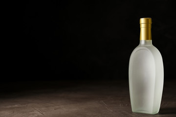 Bottle of vodka on grey table against black background. Space for text