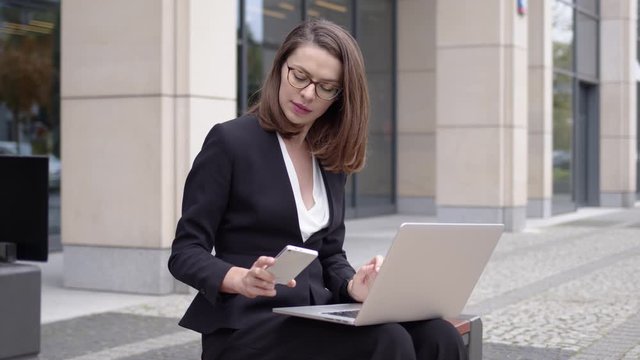 Woman in suit working with laptop on street