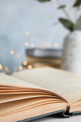 Open hardcover book on table against blurred background, closeup