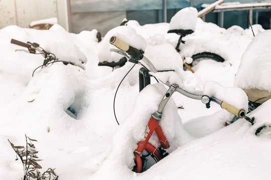 Vintage bike covered with big thick snow layer after blizzard at european city street in winter. Abandoned bicycle buried in snowstorm near building outdoor at cold weather. Scenic seasonal background