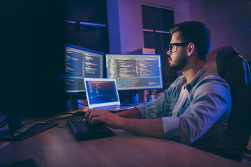 Profile side view portrait of his he nice attractive skilled smart focused concentrated guy consultant writing script creating new digital desktop app in dark room workplace station indoors - obrazy, fototapety, plakaty