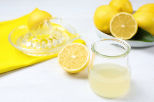 Freshly squeezed lemon juice and reamer on white wooden table