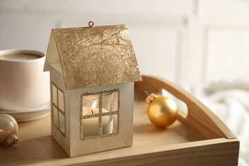 Composition with house shaped candle holder on wooden tray. Christmas decoration