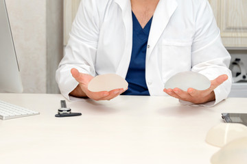 Doctor holding silicone implants for breast augmentation, space for text. Plastic surgeon hands...