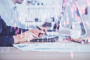 Forex graph with businessman working on computer in office on background. Concept of hardworking. Closeup. Multi exposure.