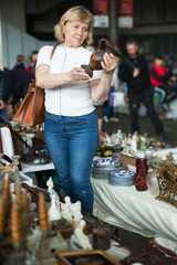 Mature woman buys handmade ceramic vase at flea market