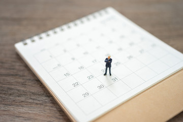 Miniature people businessmen standing on white calendar using as background business concept and finance concept with copy space  for your text or  design.