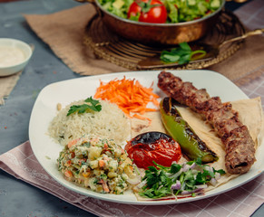 kebab with rice and vegetables in the plate on the table