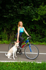A sports blonde girl with Bicycle and dog