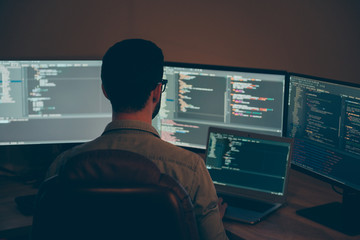 Back rear view photo of coder developing new security system to protect digital data base from being hacked using laptop as an additional work device