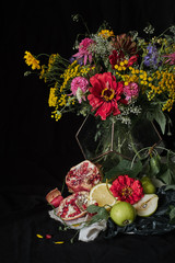 Obraz na płótnie Canvas Bouquet of flowers on a black background, next to the fruit