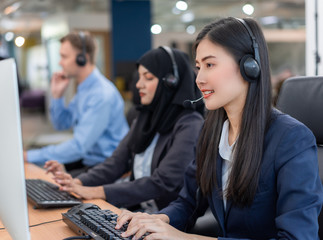 Happy smiling operator asian woman customer service agent with headsets working on computer in a call center, talking with customer for assisting to resolve the problem with her service mind