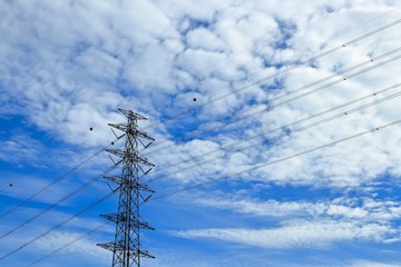 High voltage cable on electrical tower with blue sky and beautiful cloud background.