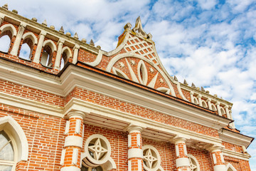 Fototapeta premium Exterior of facade of restored historical building in Tsaritsyno Park in Moscow. Bottom view against blue sky with white clouds in sunny autumn day