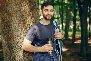 Tourist in a summer forest. Man with a map. Guy with a thermos
